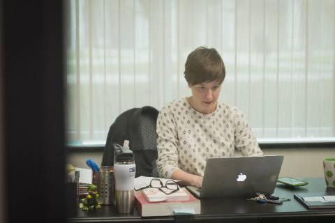一个人坐在杂乱的桌子前，用笔记本电脑工作.