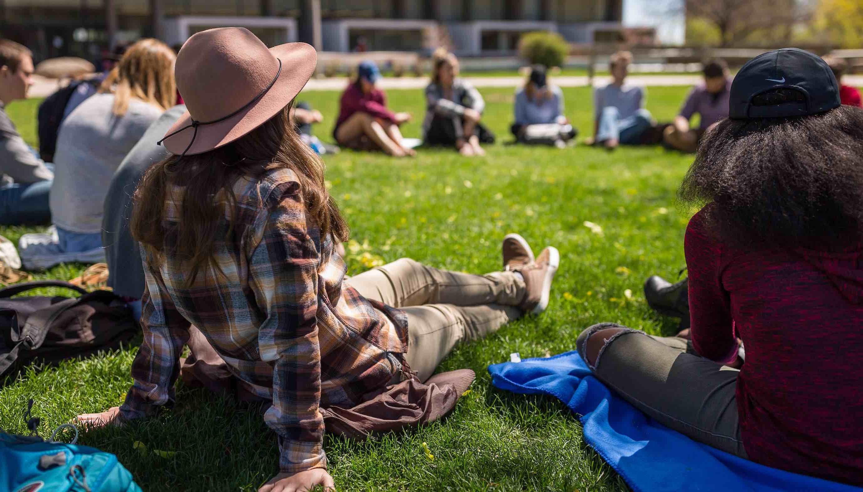 Image of students in class outside sitting in a circle.